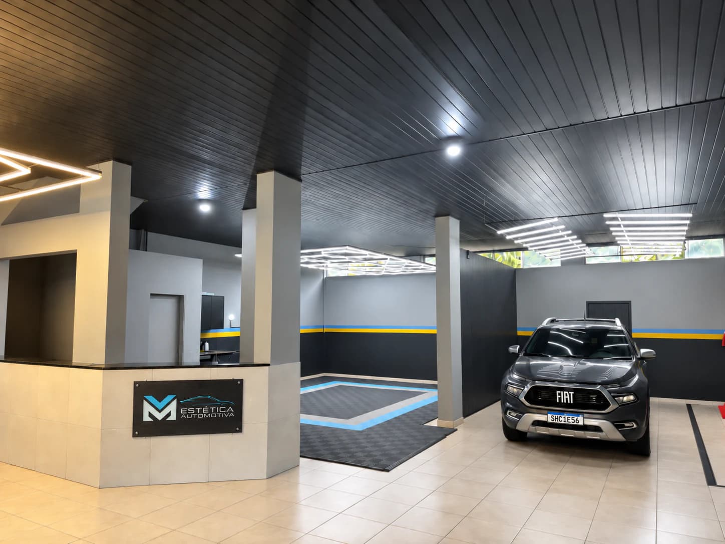 Interior renovado da MV Estética Automotiva com recepção, iluminação técnica e veículo no salão